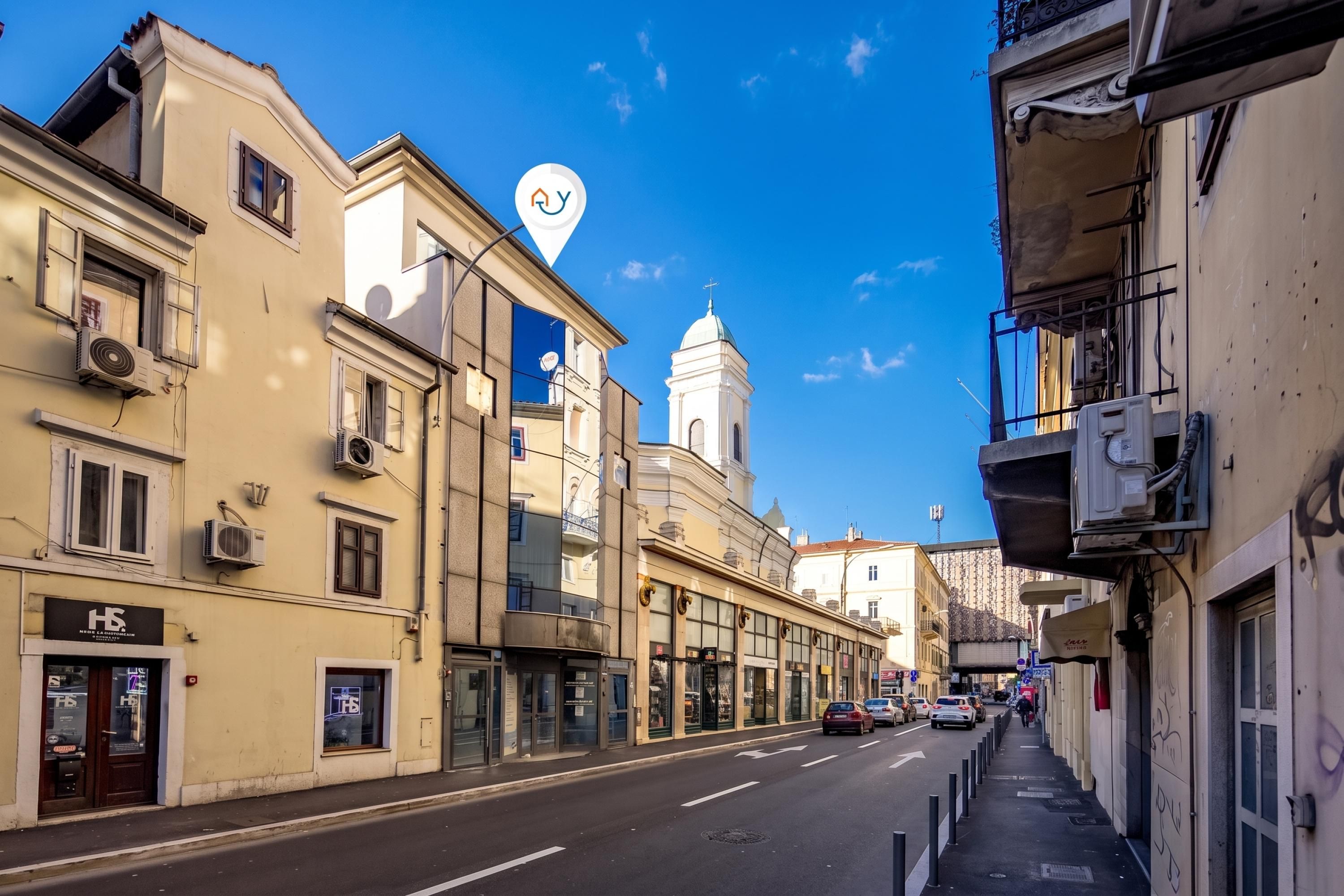 A street view with buildings, a clear sky, and a church with a dome.
