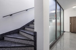 A staircase with a handrail and a door with a fire exit sign. - City Apartments (Rijeka)