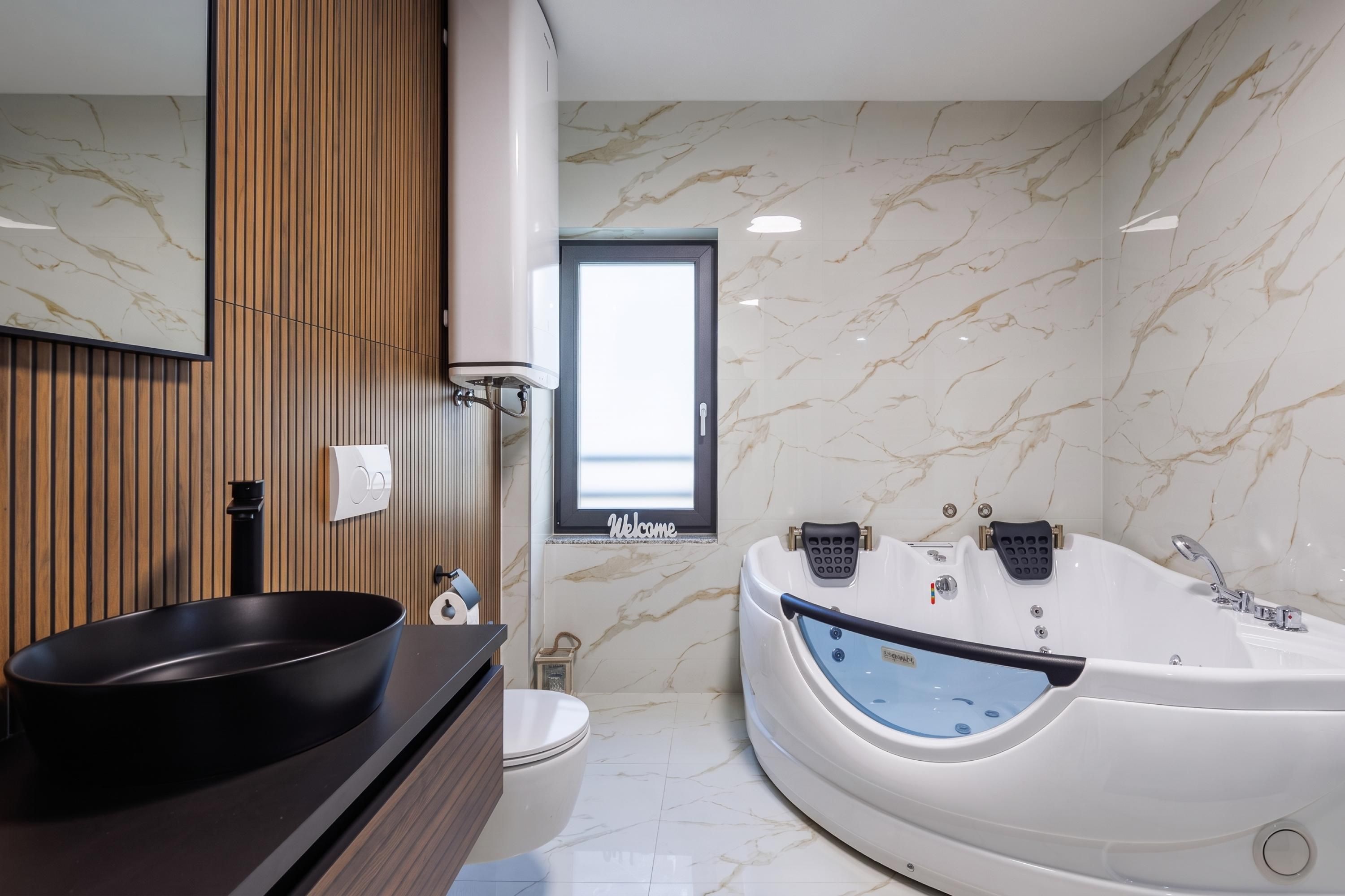 Un baño moderno con una bañera grande, un lavabo redondo y un mueble de tocador de madera.