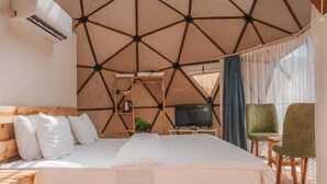 A tent-style room with a bed, a television, a small table, and a chair. - Room-rum Magic Luxury Camp (Wadi Rum)