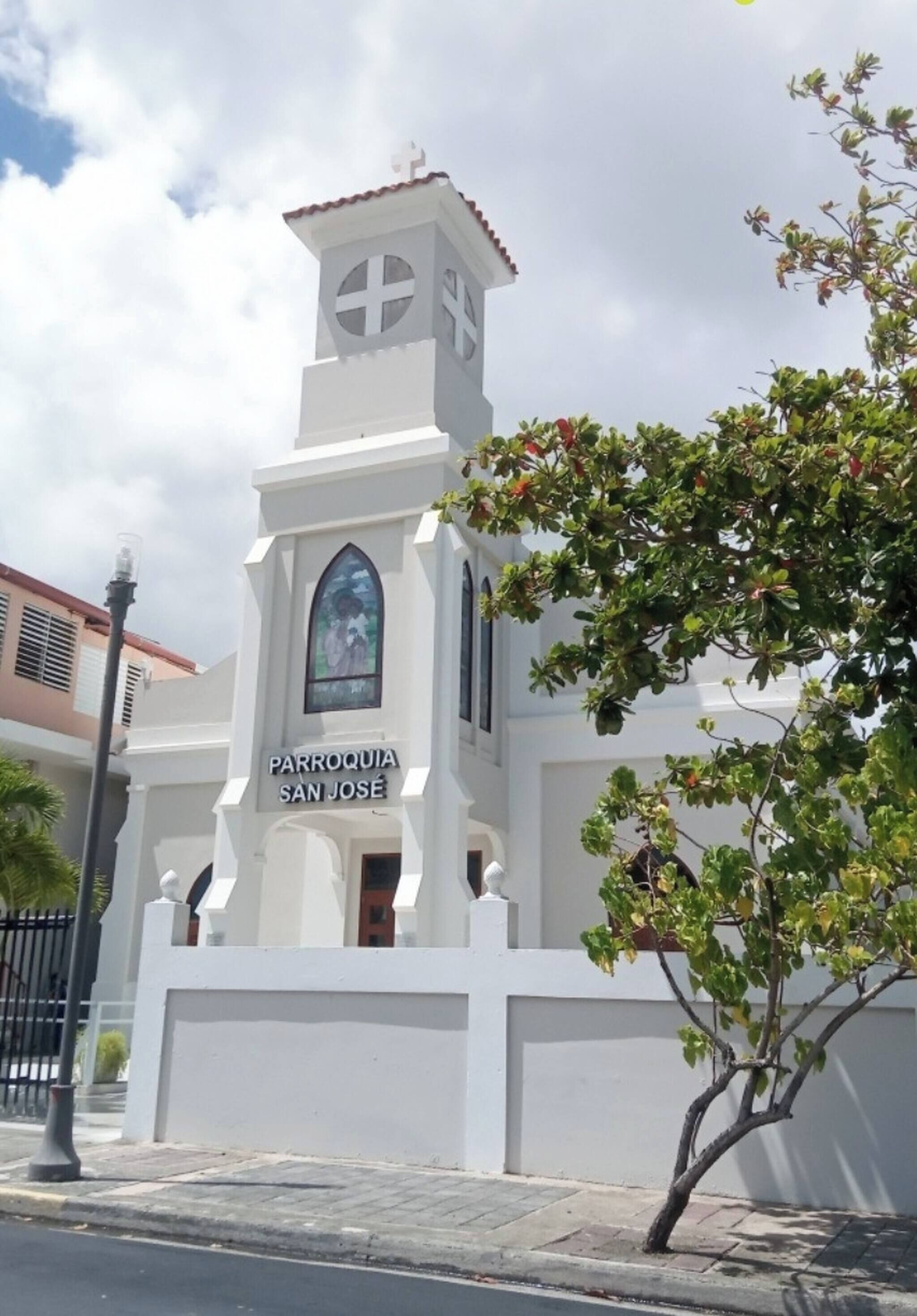 Una chiesa bianca con una torre dell'orologio e una finestra con vetrate colorate.