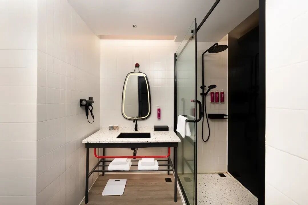 Een moderne badkamer met een douchecabine van glas, een wastafel met spiegel en een handdoekhouder.