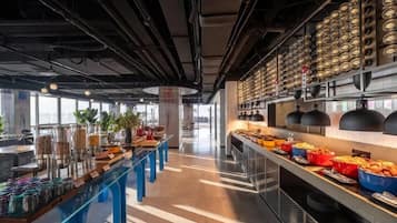 A modern kitchen area with a buffet setup, including various food containers and a long serving counter.