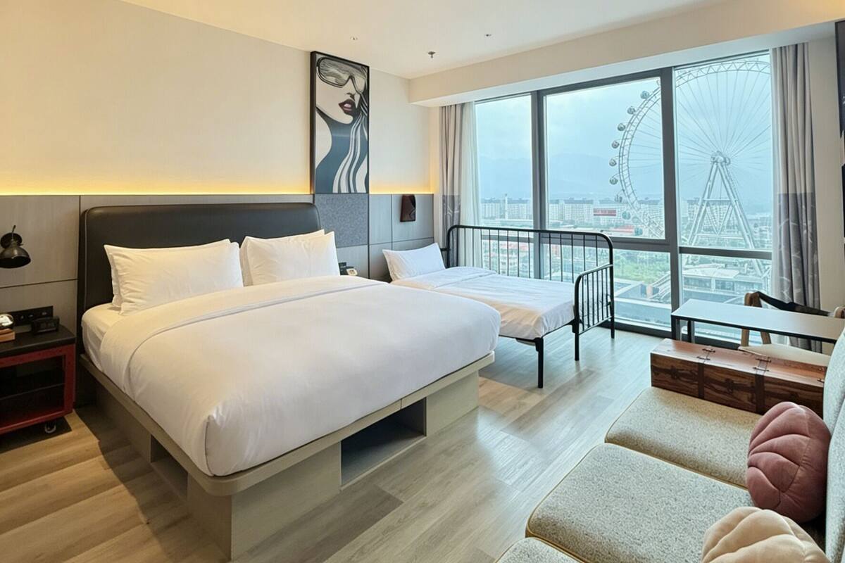 Habitación de hotel con una cama grande, un escritorio, una silla y vista a una noria.