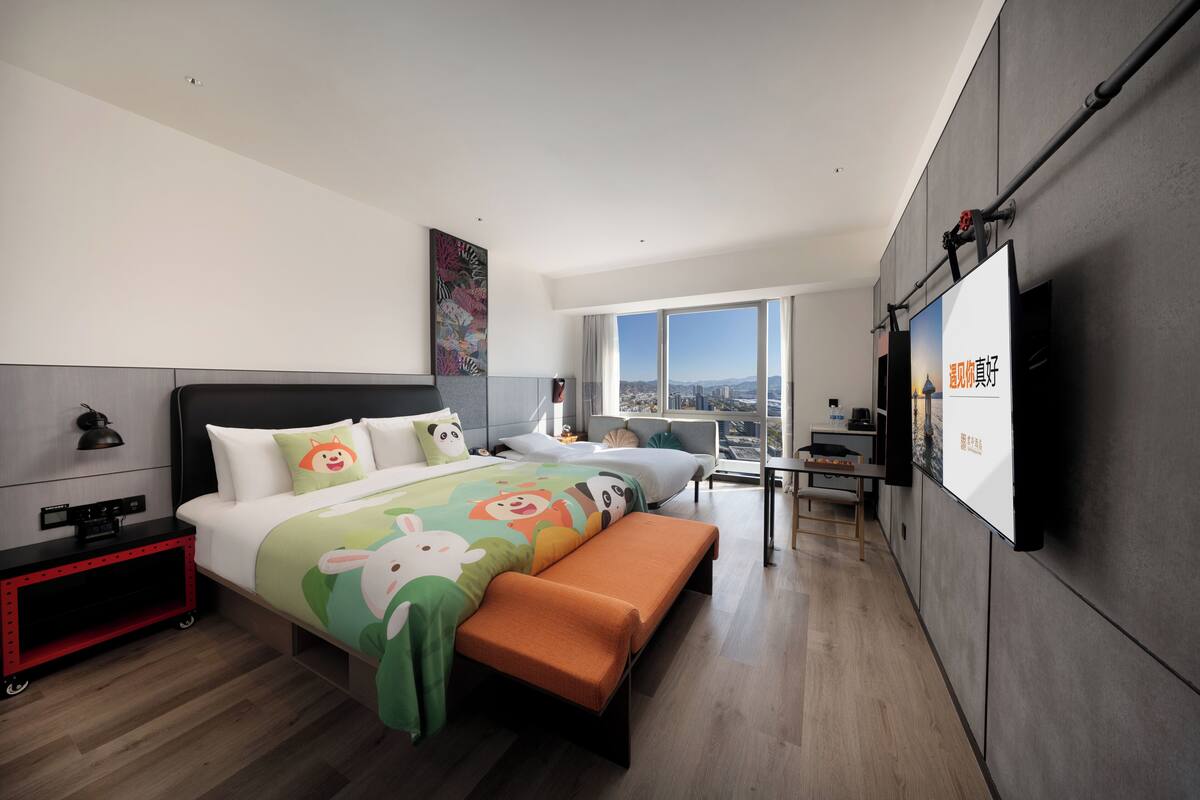 Una habitación de hotel moderna con una cama grande, un escritorio y vistas a la ciudad.
