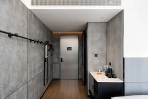Un pasillo estrecho con una puerta al final, un perchero a la izquierda y una pequeña área de kitchenette a la derecha.