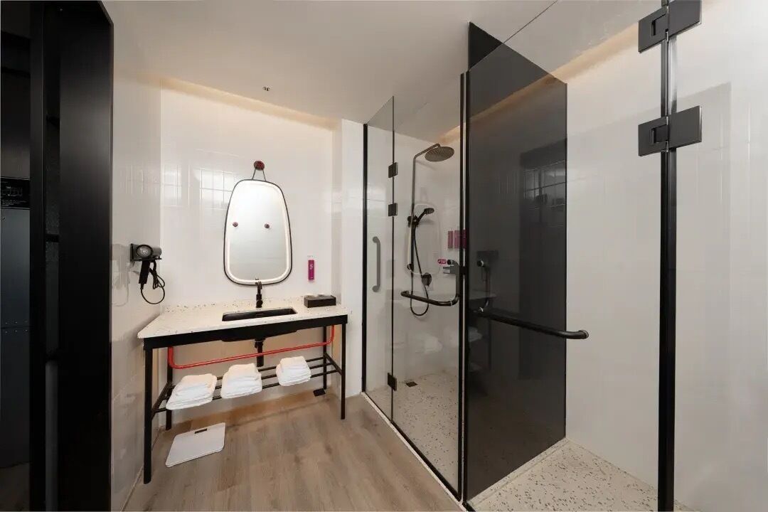 A modern bathroom with a glass shower enclosure, a vanity with a mirror, and a towel rack.