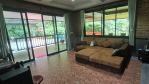 Una sala de estar acogedora con un sofá marrón, una mesita y vistas a un balcón con plantas.