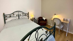 Une chambre à coucher comprenant un lit, un bureau, une chaise et une table de chevet avec des lampes.