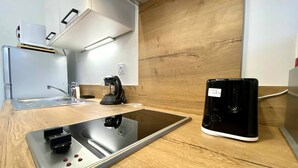 Une cuisine moderne équipée d’une plaque de cuisson à induction intégrée, d’une machine à café et d’un appareil noir posé sur le plan de travail.