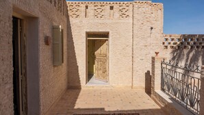 Un callejón estrecho con un edificio de piedra, una puerta de madera y una reja de metal.