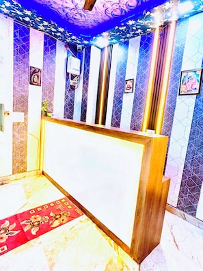 A reception area with a reception desk, patterned walls, and a red carpet. - PP GUEST HOUSE (Agra)