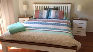 Un lit avec une couvre-lit à motifs et des oreillers, deux tables de chevet avec des lampes et une tête de lit en bois.