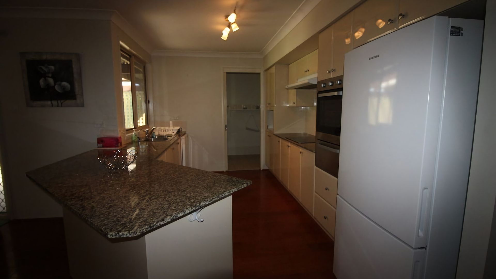 A kitchen with granite countertops, a stainless steel oven, and a white refrigerator.