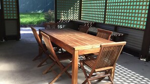 Une table à manger en bois, avec des chaises, installée dans un espace extérieur offrant une vue sur un paysage verdoyant.
