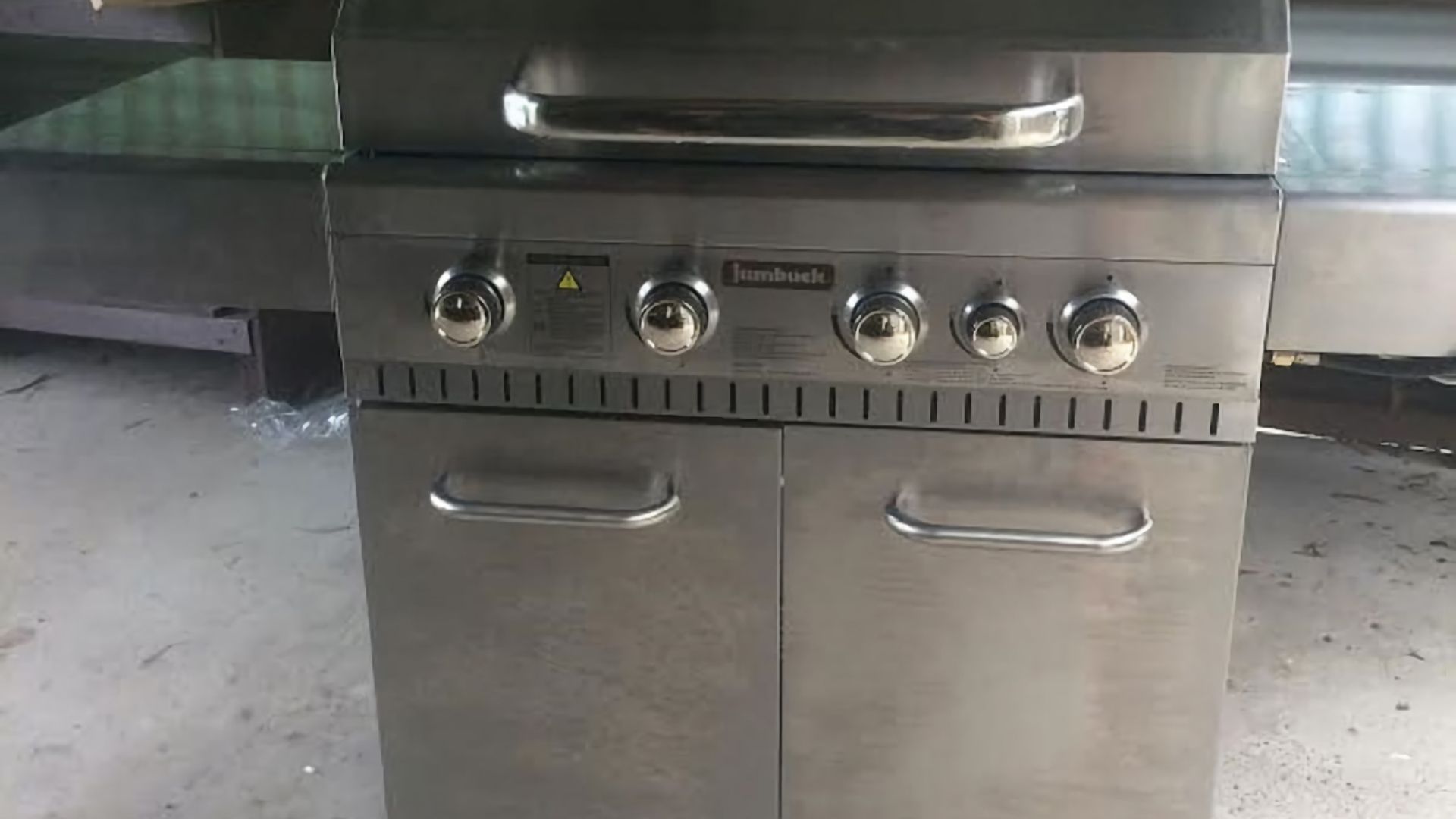 A stainless steel grill with four burners and two side handles.