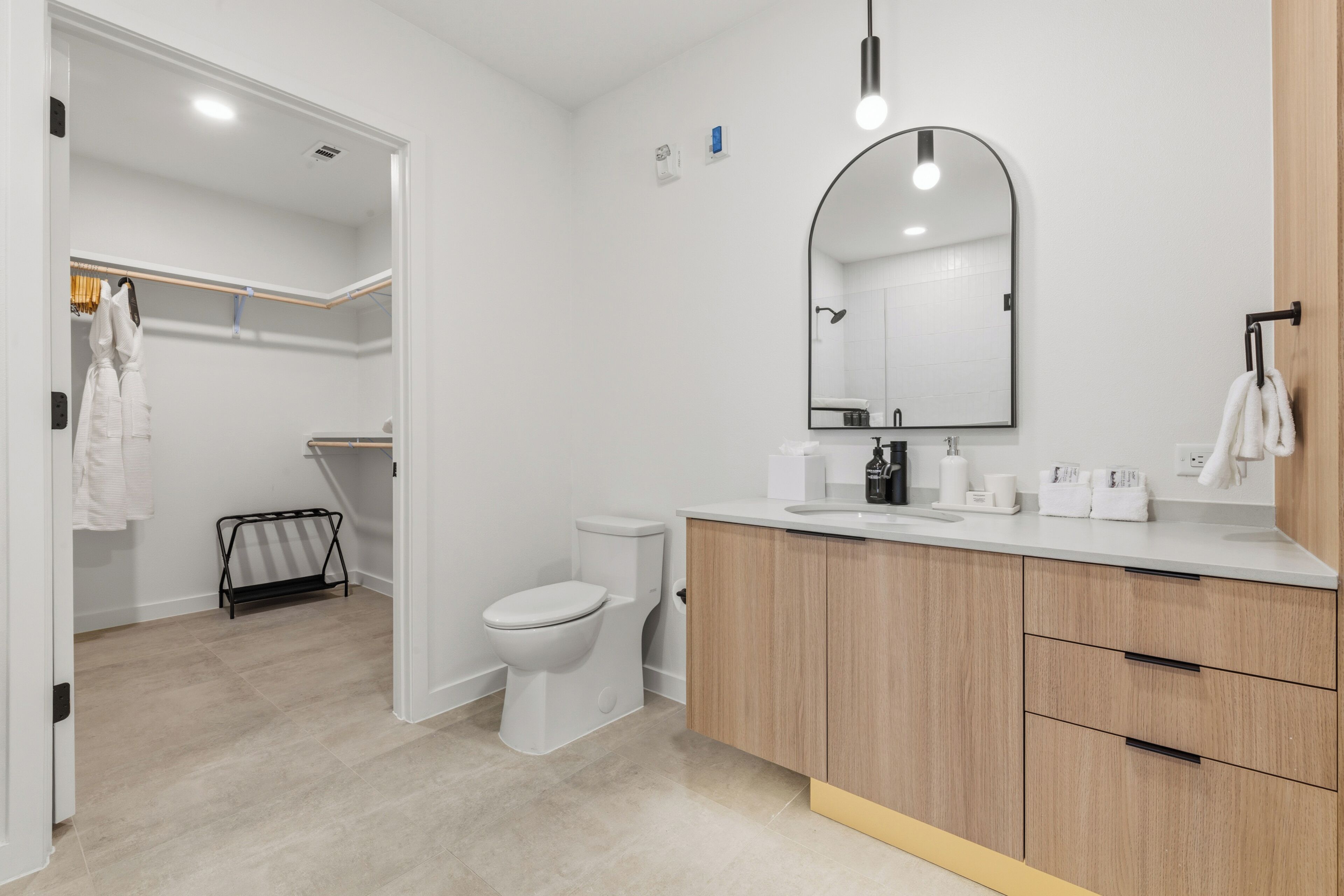 Ein modernes Badezimmer mit Toilette, Waschbecken, Spiegel und Holzschränken.