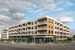 Un hôtel à plusieurs étages, doté de balcons, de grandes fenêtres et d’une façade verdoyante.