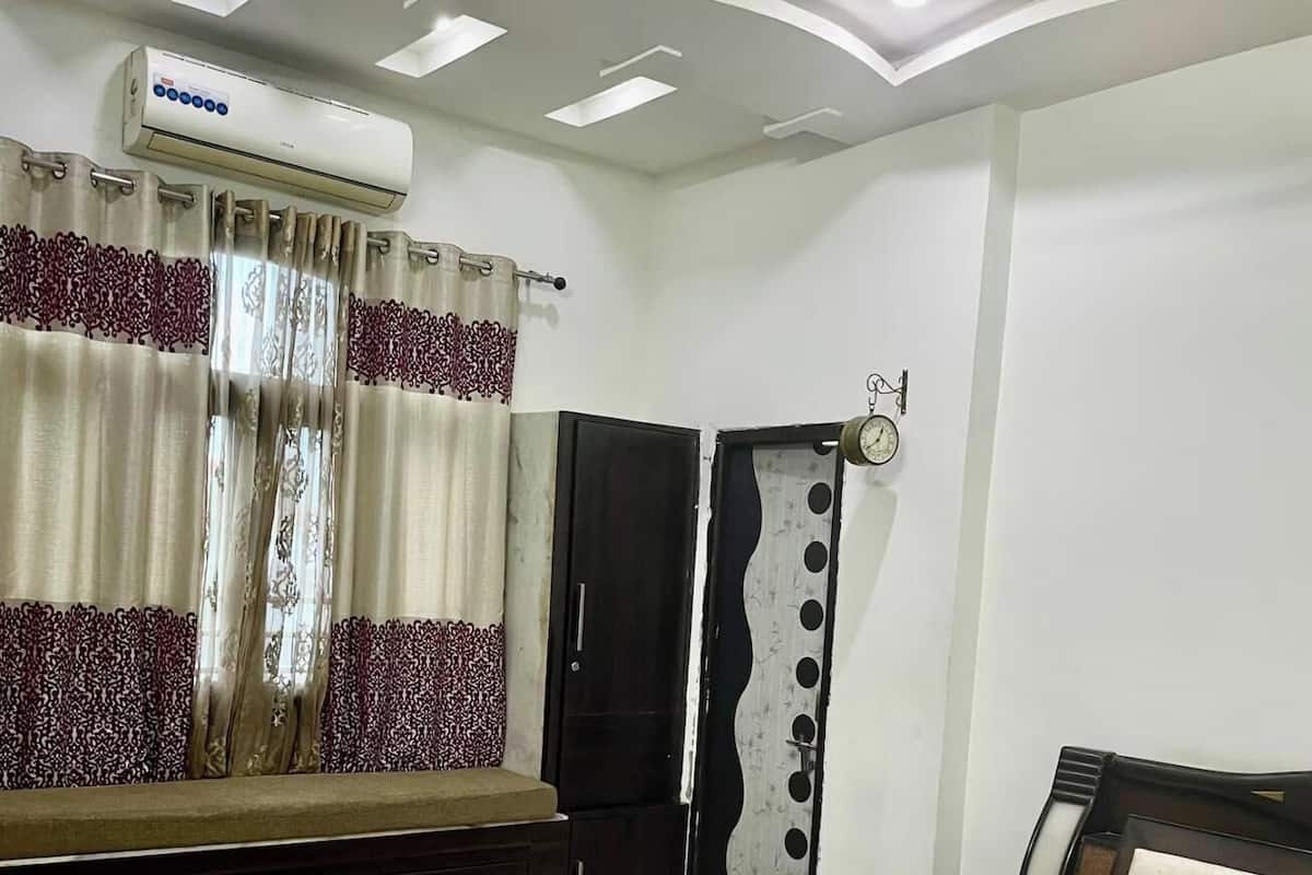 A bedroom with a bed, a wardrobe, a vanity, and a window with curtains.