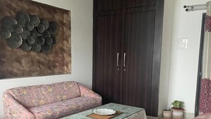 Ein Wohnzimmer mit Sofa, Couchtisch, einem dunklen Kleiderschrank und einem Wanddekor.