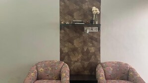 Ein Wohnzimmer mit zwei floralen Sesseln, einem Glastisch mit dekorativer Dekoration und einem Kamin mit gemustertem Wandbild.