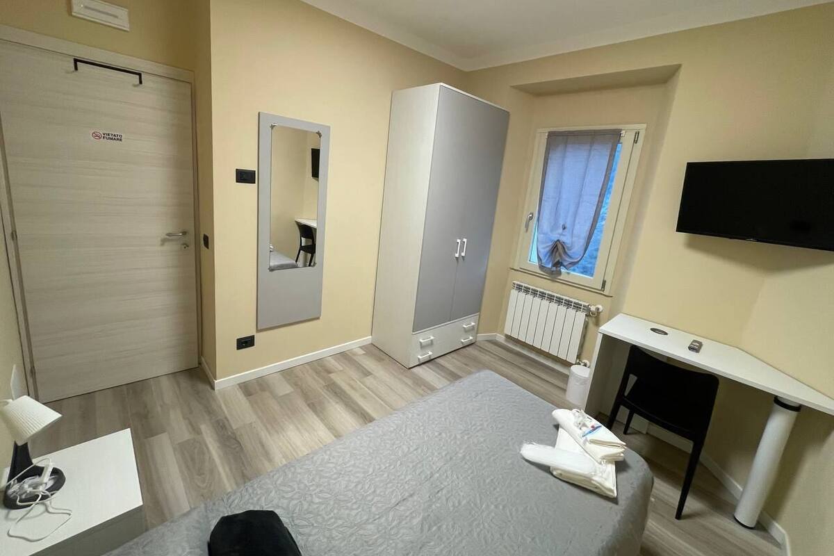 Une chambre d’hôtel comprenant un lit, un bureau, une armoire, un miroir et une télévision.