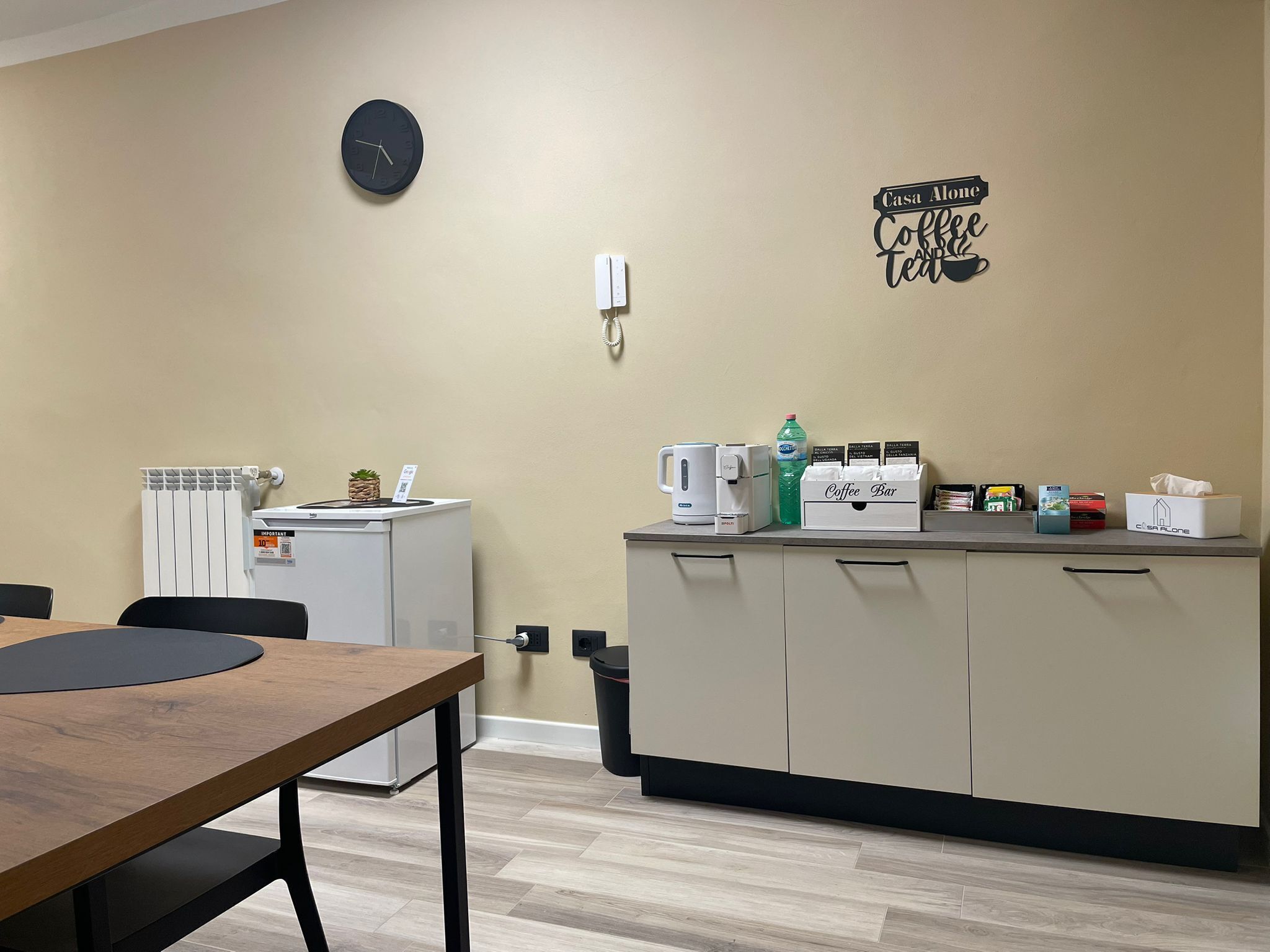 A kitchenette with a coffee maker, a water dispenser, and a coffee bar setup.