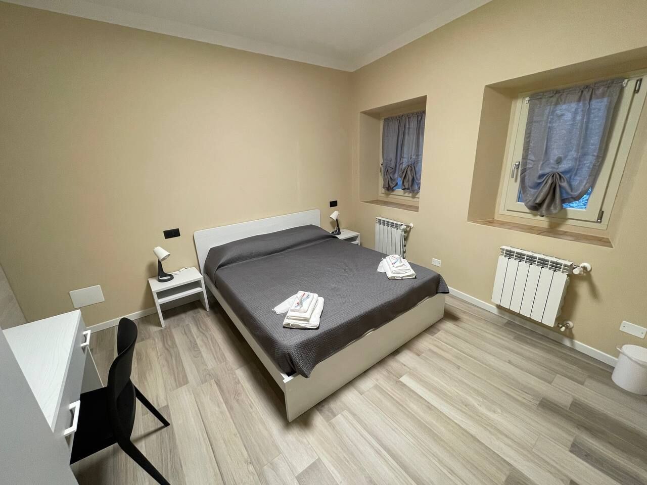 A bedroom with a bed, bedside tables, a desk, and a chair.