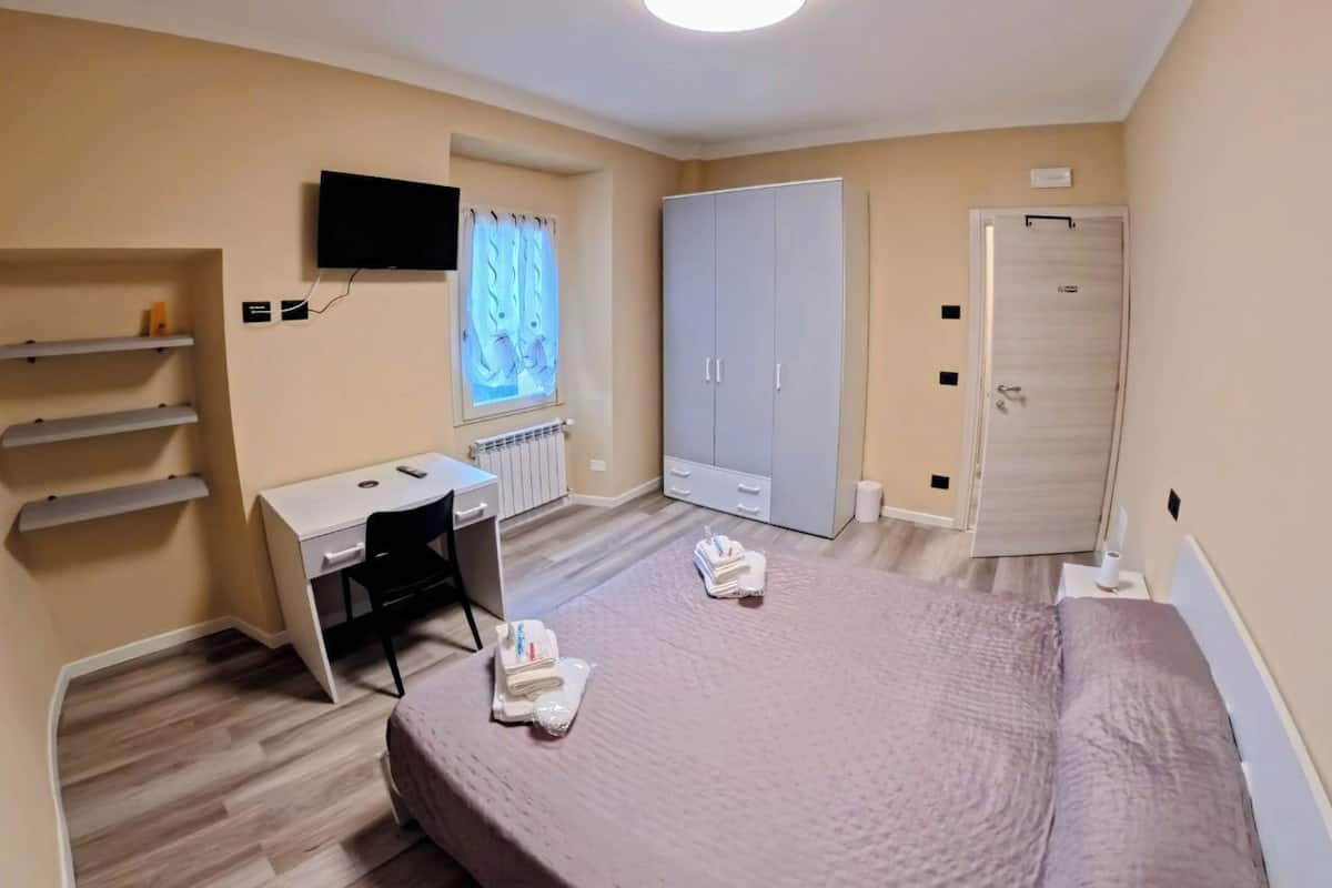 Une chambre à coucher comprenant un lit, un bureau, une armoire et un téléviseur.