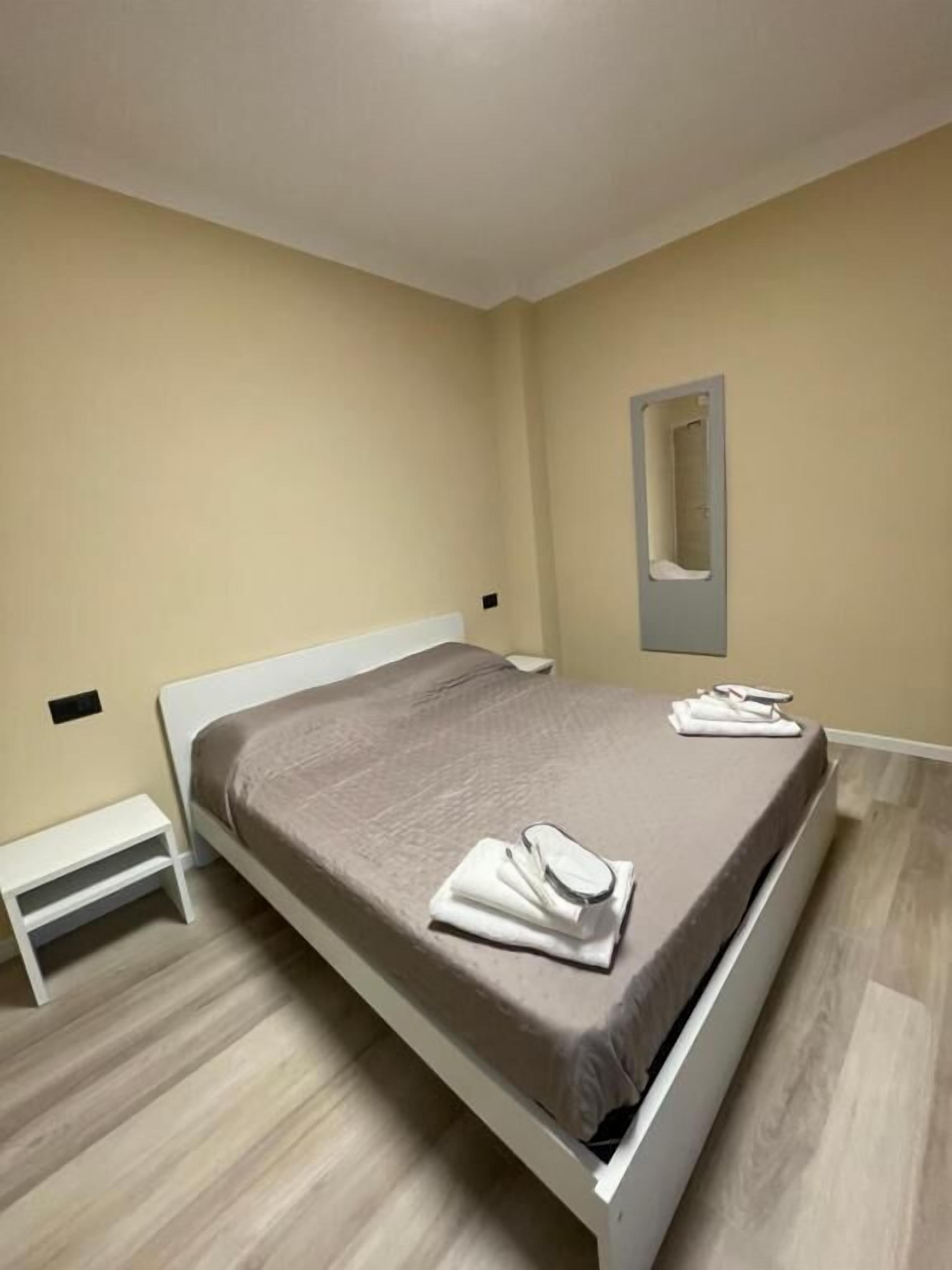 Ein Schlafzimmer mit einem Bett, einem Nachttisch, einem Spiegel und Holzboden.