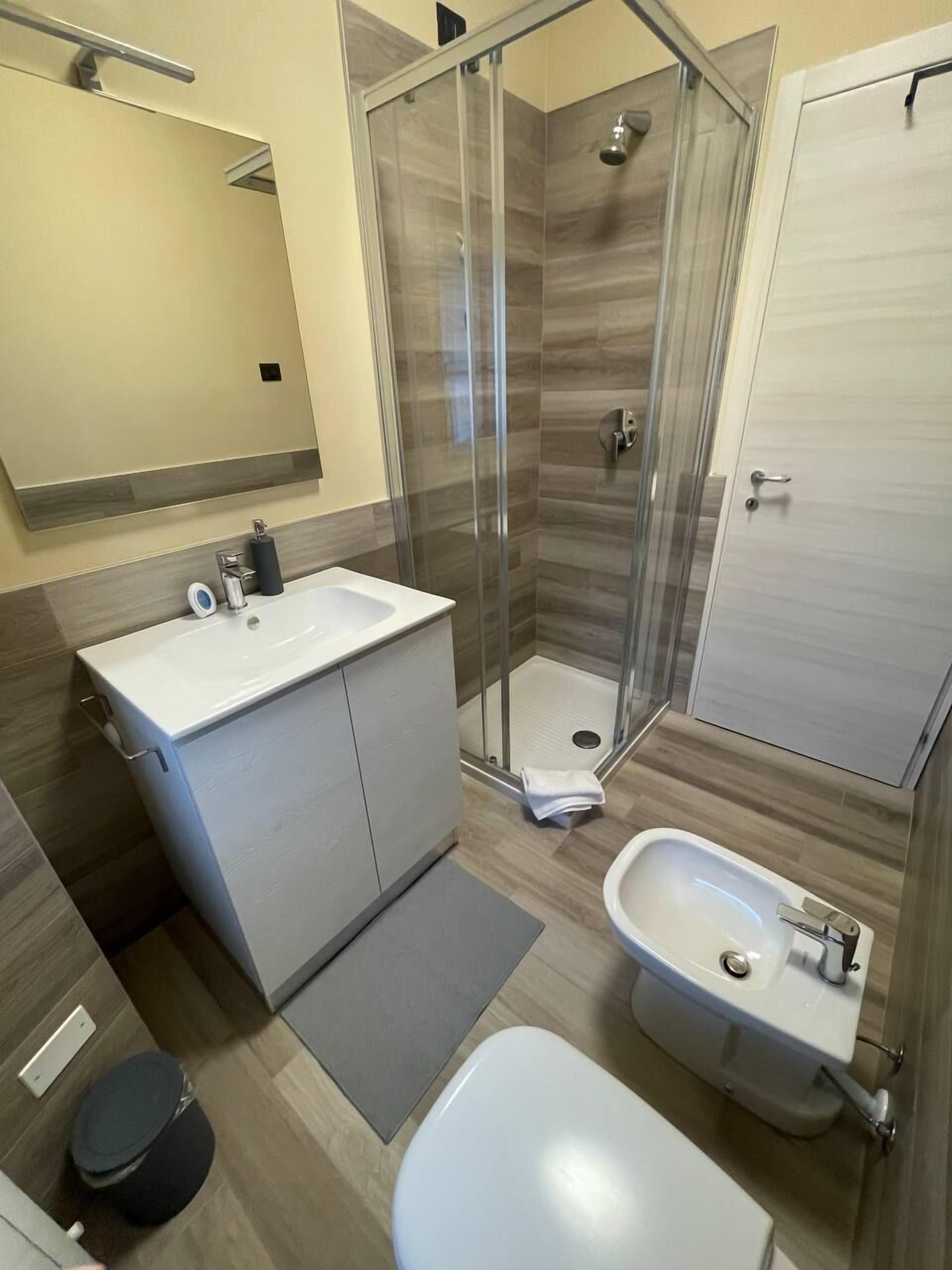A modern bathroom with a glass-enclosed shower, a vanity with a sink, and a bidet.
