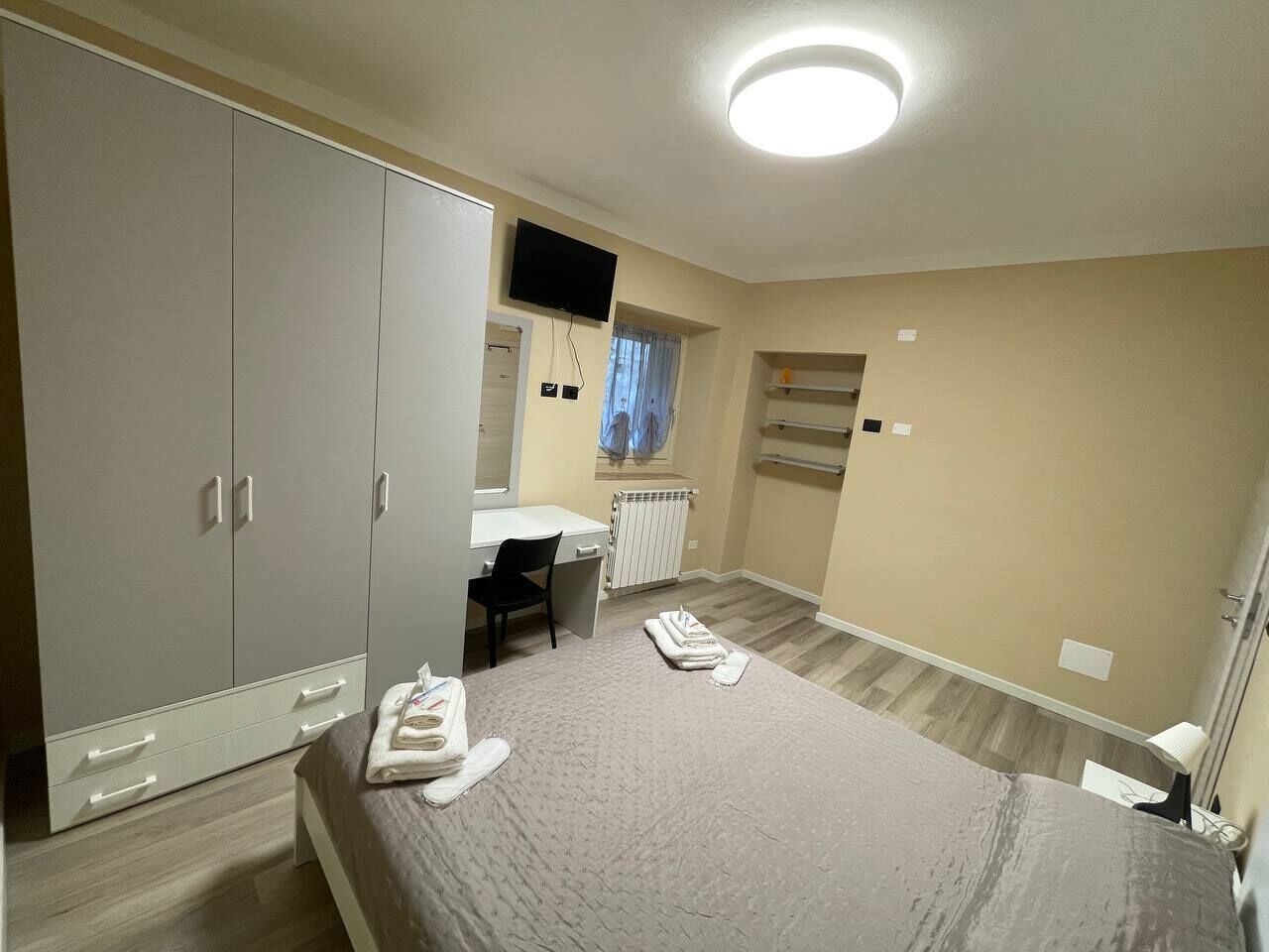 Un dormitorio con cama, escritorio, silla, armario y televisor.
