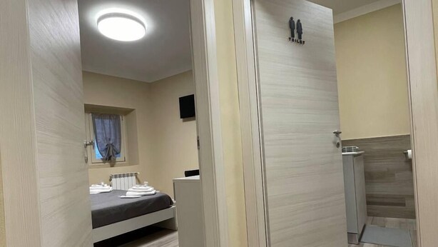 Une chambre d’hôtel avec un lit, un petit bureau, un miroir et des toilettes.