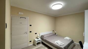 Une chambre à coucher avec un lit, des tables de chevet, une armoire et un luminaire au plafond.