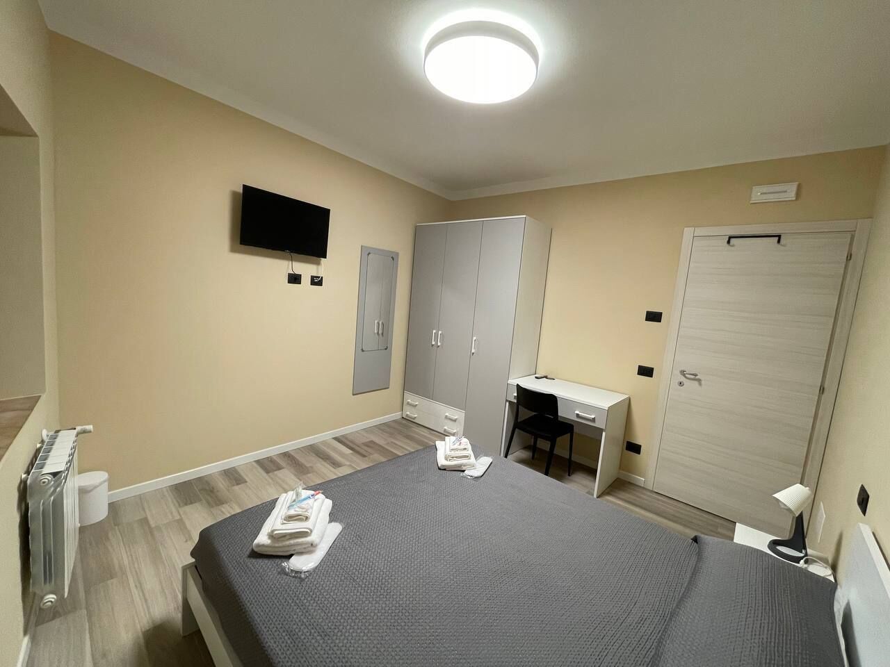 Una habitación de hotel con cama, escritorio, armario y televisor.