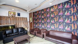 Ein Wohnzimmer mit einer schwarzen Ledersofa, einem braunen Sofa und einem Holztisch. Die Tapete zeigt ein Muster mit Städtenamen und Gebäuden.