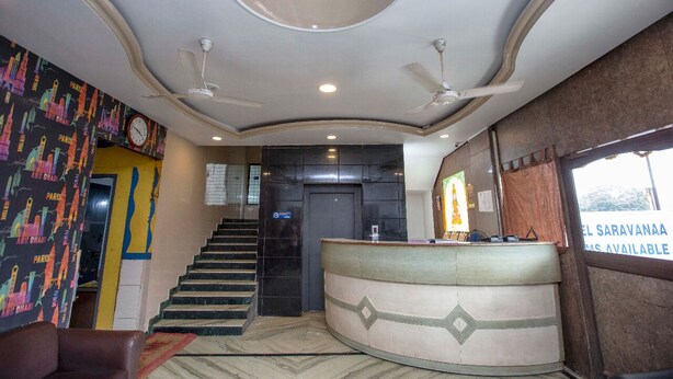 Eine Hotlellobby mit einer Rezeption, einer Treppe und einer Wand mit Stadtbild-Mural.