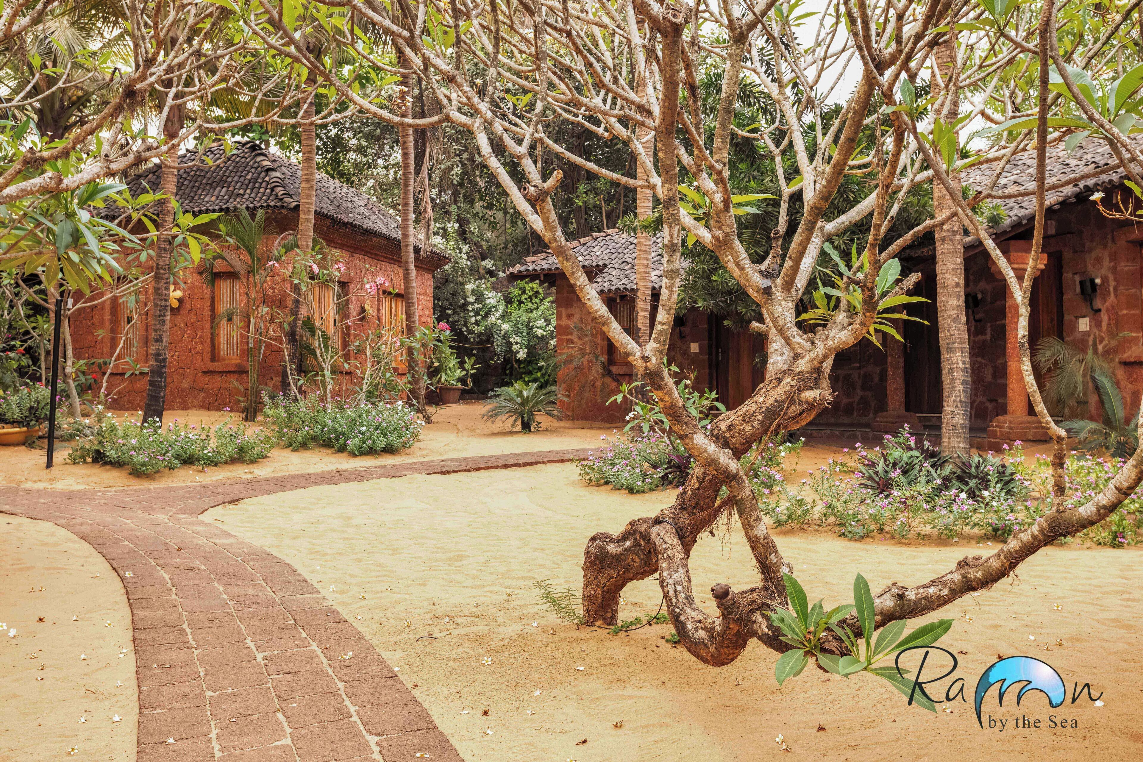 A traditional building with a tiled roof, surrounded by a garden with various plants and a curved brick pathway.