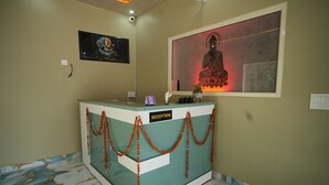 A reception desk with a 'RECEPTION' sign, a framed Buddha image, and a decorative garland. - GREEN VALLEY HOTEL AND RESORT (Haldwani)