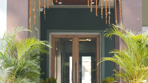 A building entrance with a wooden door, potted plants, and hanging decorations. - GREEN VALLEY HOTEL AND RESORT (Haldwani)