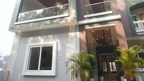 A modern two-story building with a balcony, large windows, and potted plants at the entrance. - GREEN VALLEY HOTEL AND RESORT (Haldwani)