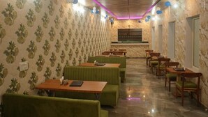 A restaurant with green booths and wooden tables, patterned wallpaper, and a wooden ceiling. - GREEN VALLEY HOTEL AND RESORT (Haldwani)