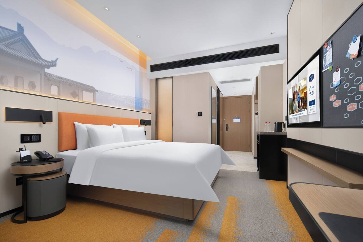 Una habitación de hotel moderna con una cama grande, un escritorio y un televisor.