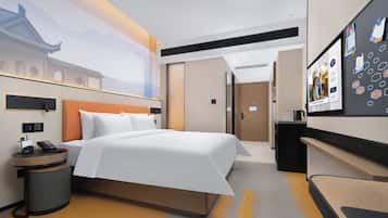 Una habitación de hotel moderna con una cama grande, un escritorio y un televisor.