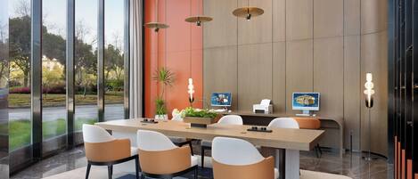A modern meeting room with a large table, six chairs, and a computer monitor.