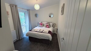 Een slaapkamer met een bed, nachtkastjes, een spiegel en een deur.