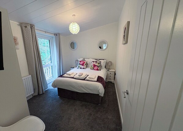 A bedroom with a bed, bedside tables, a mirror, and a door. - 2 bedroom accommodation in Cartmel (Cartmel)