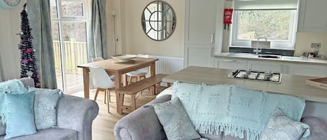 A modern kitchen with a dining area, a sofa, and a Christmas tree.