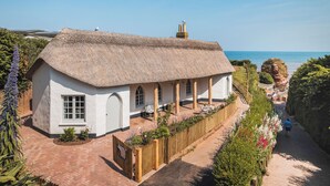 A white cottage with a thatched roof, a paved driveway, and a view of the sea. - 3 bedroom accommodation in Budleigh Salterton (Budleigh Salterton)