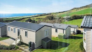 A row of mobile homes with a grassy yard and a view of the sea. - This comfortable stylish caravan offers beautiful sea and country views. (Dorchester)